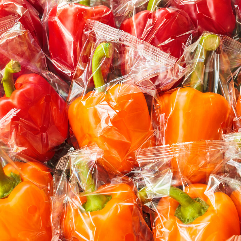 Bunch of plastic wrapped orange and red bell peppers