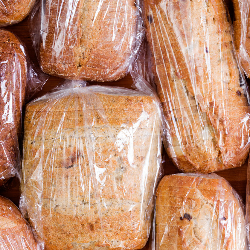 Assortment of different healthy white, wholegrain and wholewheat sliced loaves of fresh bread sealed in plastic bags ready to be distributed in a food drive, full frame overhead view